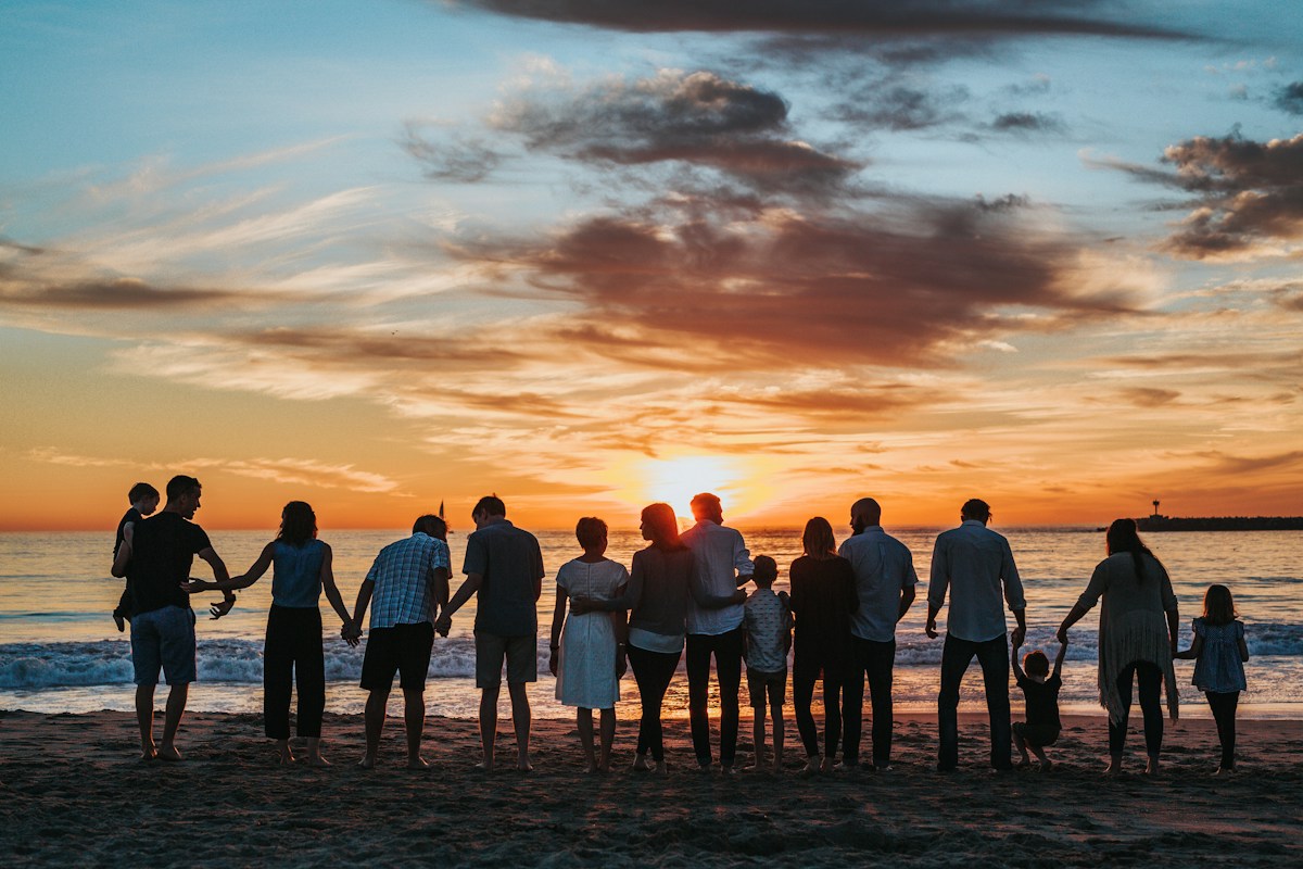 Family holding hands at the beach at sunset