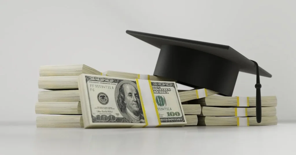 Graduation cap resting on stacked dollar bills symbolizing student loan debt and education costs